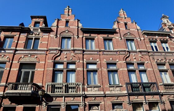 Symmetrical red brick Neo-Renaissance facade with stepped gables, intricate white stone accents, and small balconies in Antwerp, Belgium