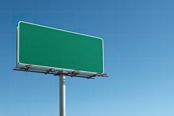 A tall, blank green roadside sign against a bright blue sky; ready for advertising copy