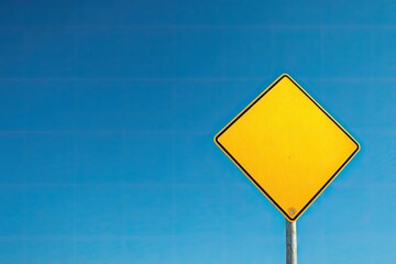 A diamond-shaped yellow road sign is mounted on a pole, against a brilliant azure sky