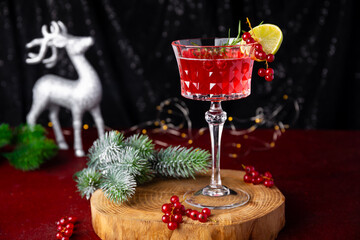 Christmas Sangria cocktail in elegant wine glass and festive decor on dark table, festive cranberry cocktail with lime