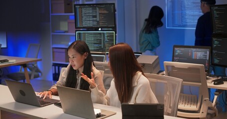 Focused group of young Asian developers working together on a coding project at night....