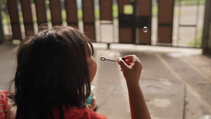 Little Girl Blowing Soap Bubbles Outdoors on a Sunny Day