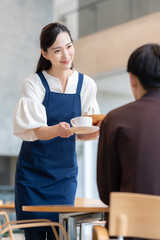 カフェで働く若い女性とお客