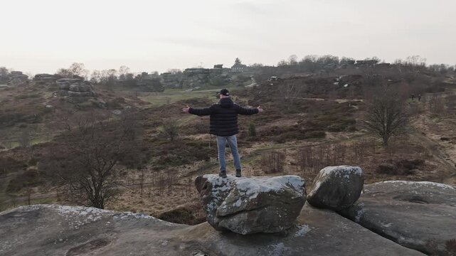 Man demonstrating satisfaction of ther landscape beauty at the Brimham rocks national park in UK. Drone POV