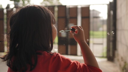Little Girl Blowing Soap Bubbles Outdoors on a Sunny Day