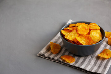 Crinkle Potato Chips with Chorizo Sausages and Onions Flavor in a Bowl, side view. Copy space.