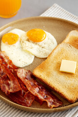 Homemade American Bacon Egg and Toast Breakfast on a Plate, side view. Close-up.