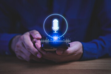 Person holding smartphone with glowing microphone icon and sound wave hologram, symbolizing voice...