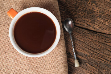 Hot chocolate in orange cup on wooden table.