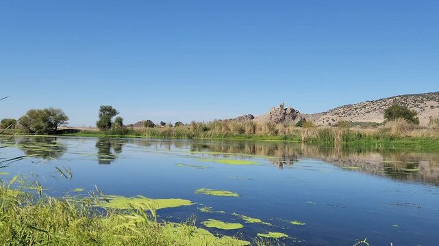 In Osmaniye Turkey, Amouda castle (Hemite kalesi), stands majestically above Ceyhan river, its ancient stone walls and towers reflected in calm waters, creating a serene and picturesque scene in fall