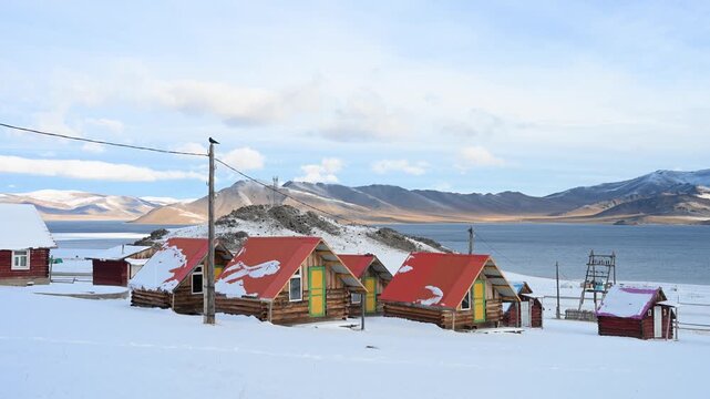 Rustic wooden cabins offer accommodation for tourists at a remote camp on the shores of Mongolia's Terkhiin Tsagaan Nuur (White Lake). A serene and isolated winter travel destination.