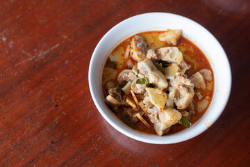 Pork curry in a white plate placed on a wooden table