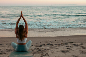 Woman enjoys yoga at sunset on the beach in Santa Barbara, California.