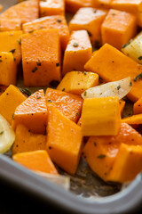 chopped butternut squash onion and garlic with herbs and spices in tray ready to roast