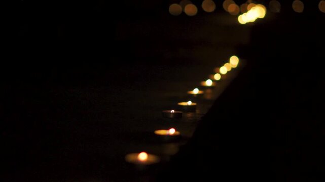 Row of lit Diyas with flickering flames against dark background. Closeup shot of the Diya on the wall during the Diwali festival in India. Indian festival.
