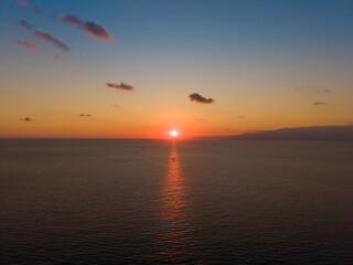 Golden sunset reflecting on sea with a small boat in reflection