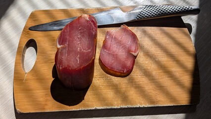 Sliced Meat Beautifully Arranged on a Cutting Board with a Sharp Knife Beside It