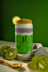Tropical kiwi and taro smoothie with ice, cream foam, and mint leaf for fresh summer concept.
