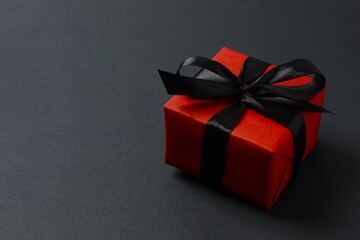 Beautifully wrapped gift box with black ribbon on dark background