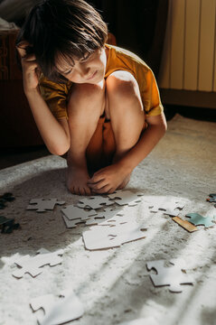 Child sitting on carpet at home solving puzzle in sunlight