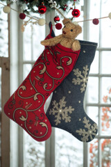 Cozy christmas stockings with a teddy bear hanging by the window