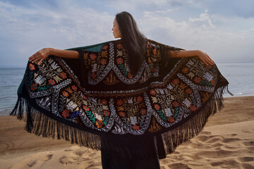 Woman in colorful traditional chapan with embroidery on beach