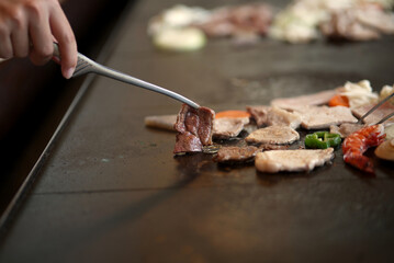 Traditional Japanese barbecue on a volcanic stone grill, capturing the sizzling moment and smoky aroma of barbecue cooking.