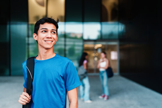 Student with backpack smiling outdoors on university campus