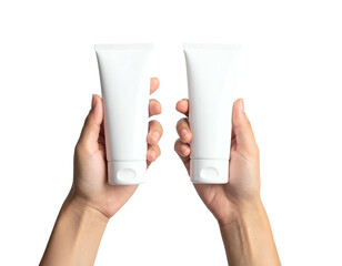 Two white cosmetic tubes held upright by two hands against a stark black background