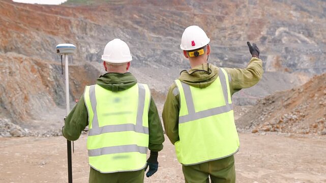 Team Workers surveyor in uniform use theodolite to verify coordinates on open pit mine, mining concept.