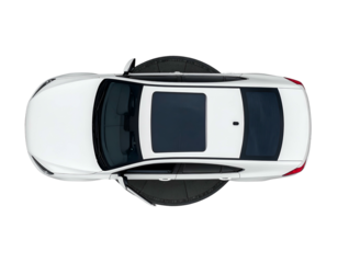 Overhead shot of a white passenger car with sunroof, set on a black rotating platform