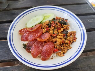 Stir-fried minced pork with holy basil served with fried Chinese sausage and cucumber