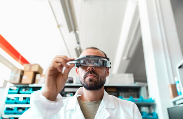 Lab technician using magnifying glasses in high tech electronics workshop