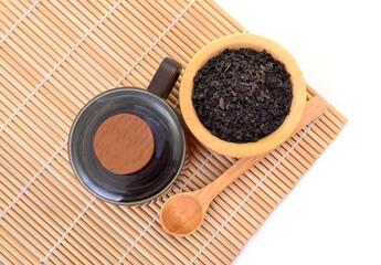 Black tea with wooden bowl and cup on bamboo mat