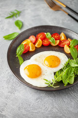 Fried eggs and Caprese salad with tomatoes, mozzarella cheese and basil leaves in a plate.
