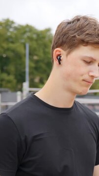 Young man in sportswear listening to music with wireless earbuds for focus during fitness