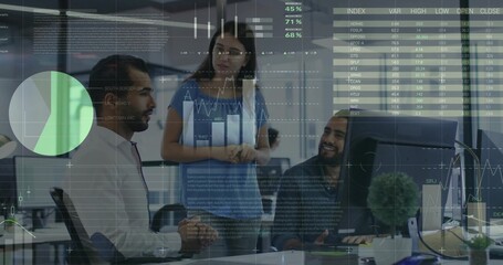 Collaborating colleagues reviewing analytics at computer monitor in office, displaying data charts