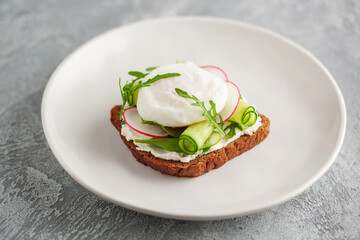 Open sandwich with vegetables and poached egg in a plate on the table