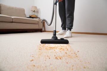 A Focused Individual Engaging in Carpet Cleaning with a Vacuum Cleaner, Removing Small Debris and Maintaining Home Hygiene
