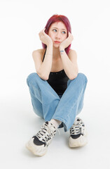 Asian pretty confident young woman purple hair sitting 
posing wearing black sleeveless top blue jeans on white background in studio modern street outfit fashion portrait casual attitude trendy style.