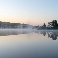 Fototapeta premium Soft mist over calm lake during sunrise showing peaceful natural reflection