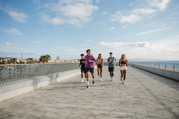 A group of five athletes are running and smiling