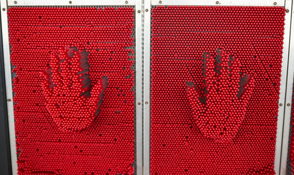 Handprints on a large red pin art toy.