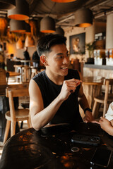A man sits at a table and smiles while looking away