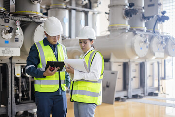 Engineers team inspecting high-voltage gas-insulated switchgear (GIS) at a power substation, using digital tablets and reports to ensure energy system reliability, safety, energy infrastructure