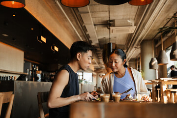 A woman and a man are sitting at a table and looking at a plate of food
