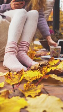 Cozy autumn morning on a wooden terrace with warm socks, blanket, and coffee. Peaceful fall mood, golden leaves, soft light, sweater weather lifestyle and comfort in nature.