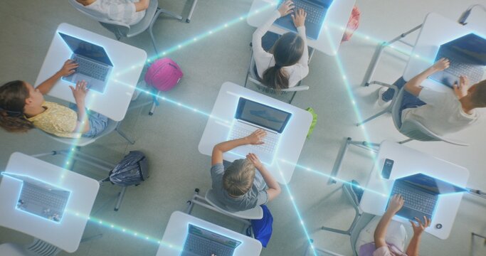 Children Interacting With Laptops, Tablets in Modern Classroom, Surrounded by Glowing Digital Connections. Concept Technology Integration and Prevalence of Artificial Intelligence. Rotating Top View.