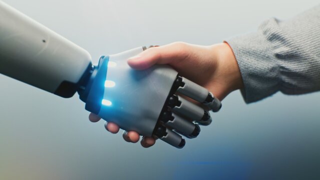 Close up of Human and Robotic Hand Shaking, Glowing With Digital Light. Human and Robot Handshake Symbolizing AI Collaboration. Concept of Connection Between People and AI in Future Technology.