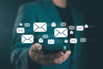Businessman using smartphone with floating email icons, concept of online communication, digital marketing, email notification, technology network, and modern business connection.